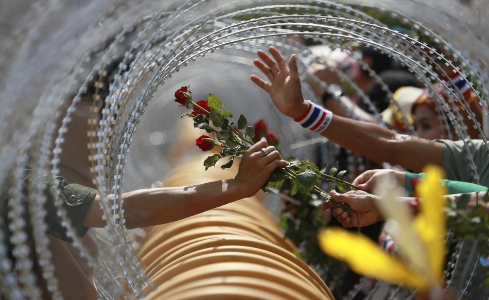 Un manifestant anti-gouvernement donne une rose à un soldat thaïlandais au ministère de la Défense lors d'un rassemblement à Bangkok.